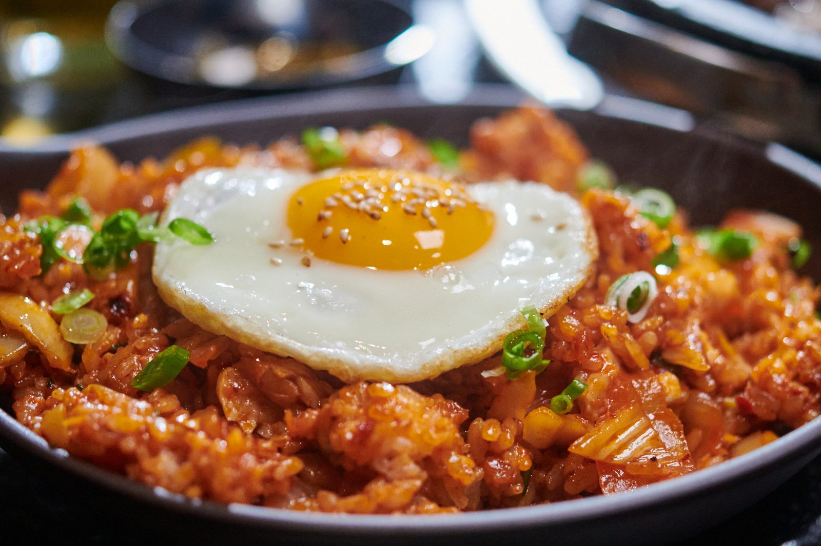 석화한우암소생구이 석화한우 비빔볶음밥 — 검은 팬에 담긴 빨간 양념 볶음밥 위에 반숙 달걀프라이와 깨, 송송 썬 쪽파를 올렸다.